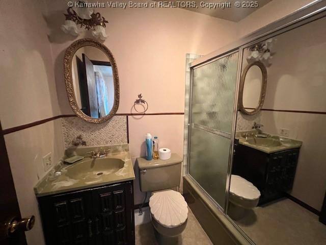 full bathroom featuring enclosed tub / shower combo, vanity, and toilet