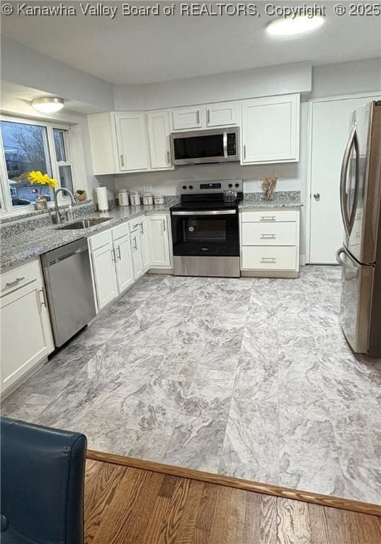 kitchen featuring sink, white cabinetry, light stone counters, and appliances with stainless steel finishes