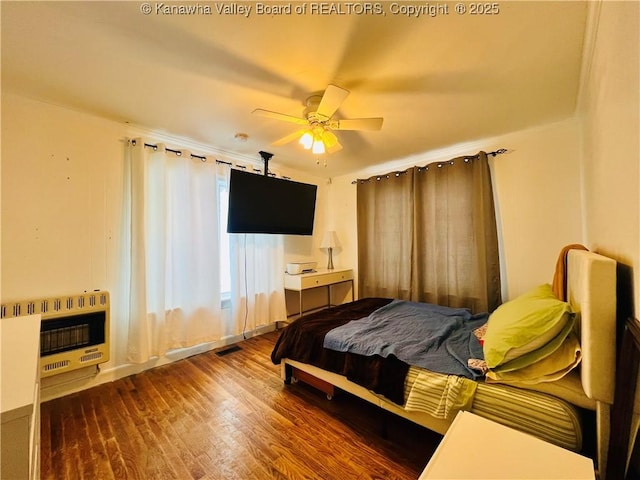 bedroom with ceiling fan, hardwood / wood-style flooring, and heating unit