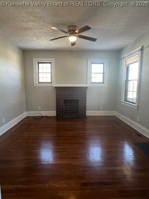 unfurnished living room featuring a brick fireplace, dark wood-type flooring, a textured ceiling, and ceiling fan