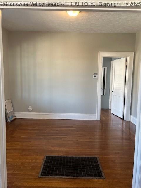 unfurnished room with dark wood-type flooring and a textured ceiling