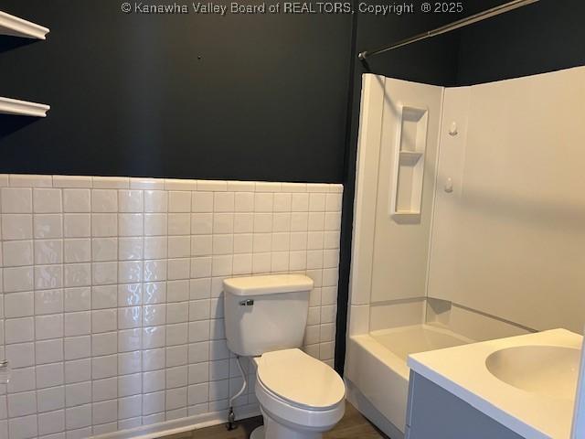 full bathroom with bathtub / shower combination, toilet, vanity, and tile walls