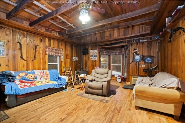 interior space featuring ceiling fan, hardwood / wood-style floors, beam ceiling, wooden ceiling, and wood walls