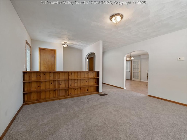 carpeted empty room with a textured ceiling and a notable chandelier