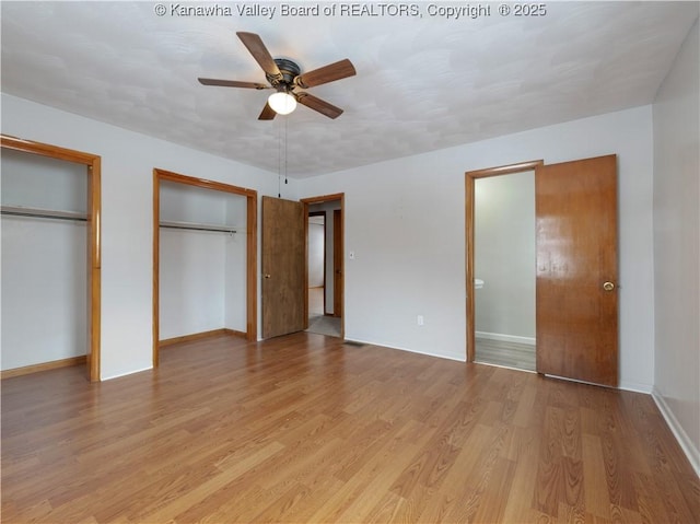 unfurnished bedroom with ceiling fan, light hardwood / wood-style flooring, and two closets