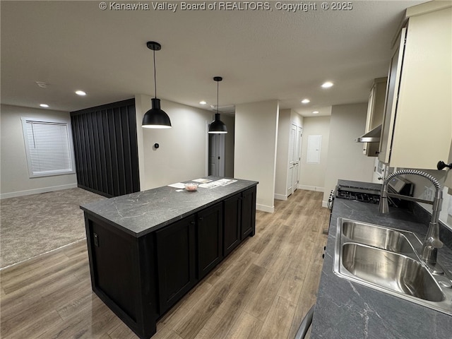 kitchen featuring sink, a center island, hanging light fixtures, dark stone countertops, and hardwood / wood-style floors