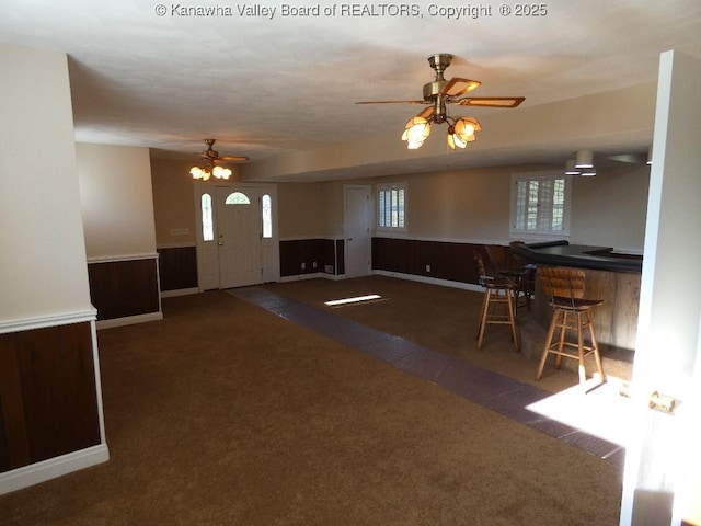 interior space featuring indoor bar, dark carpet, and ceiling fan