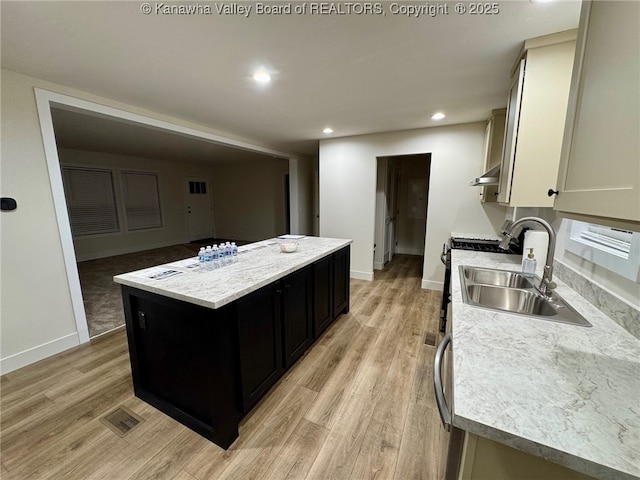 kitchen featuring sink, a center island, white cabinets, and light wood-type flooring