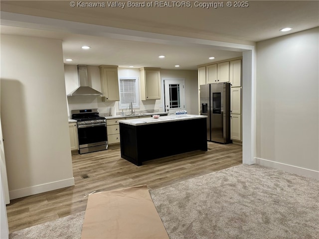 kitchen with sink, stainless steel appliances, a center island, cream cabinetry, and wall chimney exhaust hood