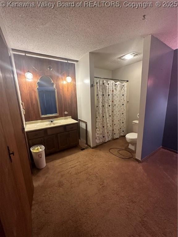 bathroom with vanity, toilet, a textured ceiling, and walk in shower