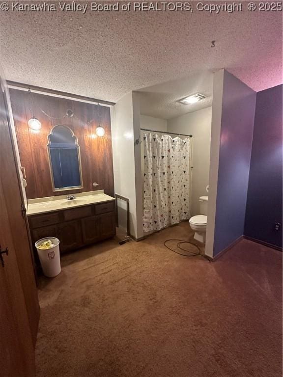 bathroom featuring walk in shower, vanity, toilet, and a textured ceiling