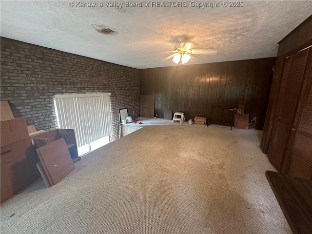 interior space with ceiling fan, a textured ceiling, and wood walls