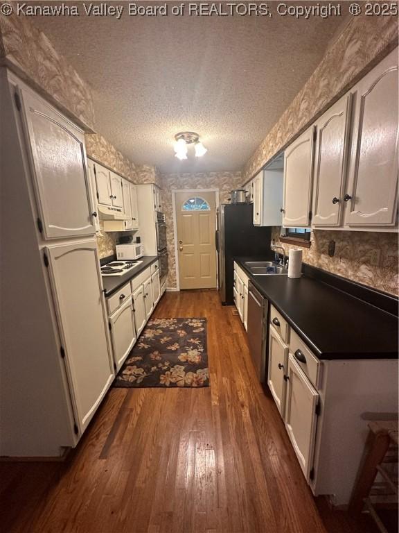 kitchen with sink, stainless steel appliances, dark hardwood / wood-style floors, white cabinets, and a textured ceiling