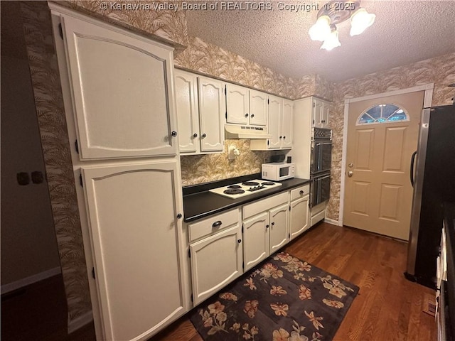 kitchen with white cabinetry, dark hardwood / wood-style floors, a textured ceiling, and white appliances