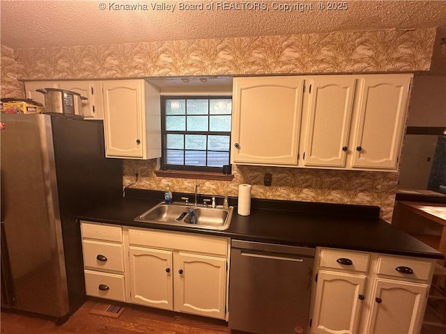 kitchen with stainless steel appliances, white cabinetry, and sink