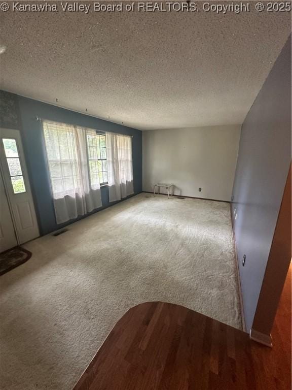 carpeted empty room with a textured ceiling