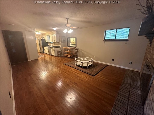 unfurnished room with hardwood / wood-style flooring, ceiling fan, a fireplace, and a textured ceiling