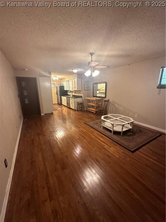 unfurnished living room featuring ceiling fan, dark wood-type flooring, and a textured ceiling