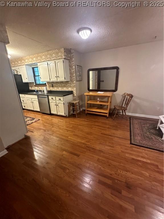 kitchen featuring backsplash, dark hardwood / wood-style flooring, white cabinets, stainless steel dishwasher, and a textured ceiling