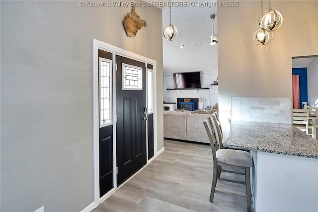 foyer entrance with ceiling fan, a fireplace, and light hardwood / wood-style floors