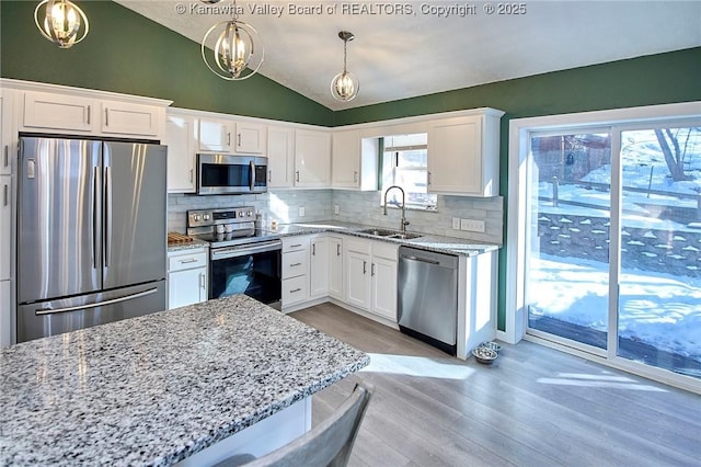 kitchen with stainless steel appliances, vaulted ceiling, hanging light fixtures, and sink