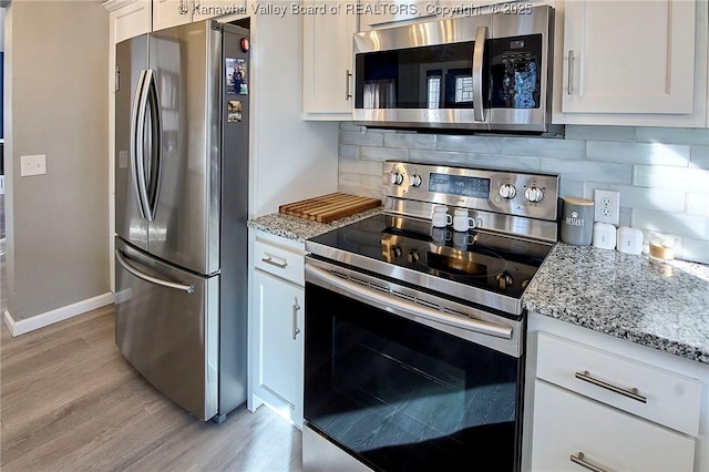 kitchen featuring decorative backsplash, light stone countertops, white cabinets, and appliances with stainless steel finishes