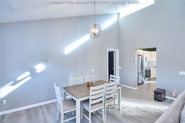 dining room with a towering ceiling, a notable chandelier, and light hardwood / wood-style floors