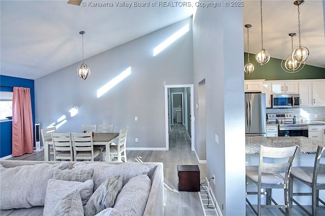 living room featuring an inviting chandelier, high vaulted ceiling, and light hardwood / wood-style flooring