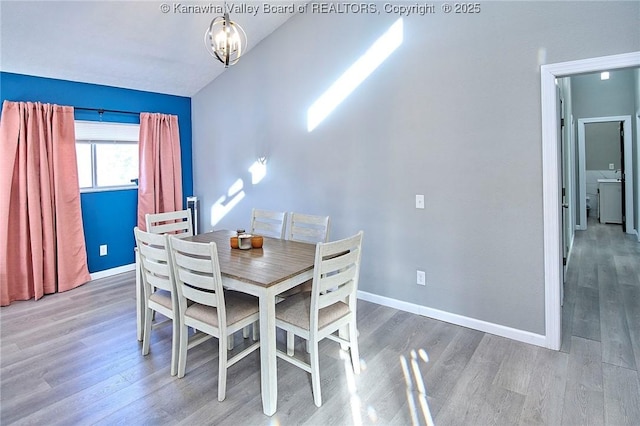 dining area with wood-type flooring, washer / clothes dryer, and a notable chandelier