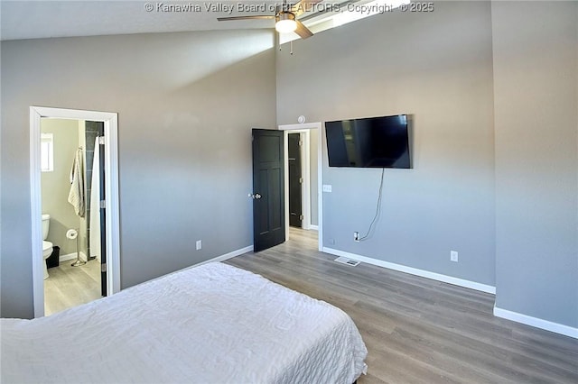 bedroom with ensuite bathroom, high vaulted ceiling, wood-type flooring, and ceiling fan