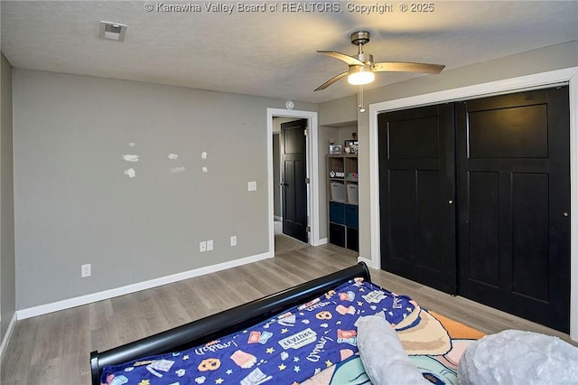 bedroom with a textured ceiling, light hardwood / wood-style flooring, a closet, and ceiling fan