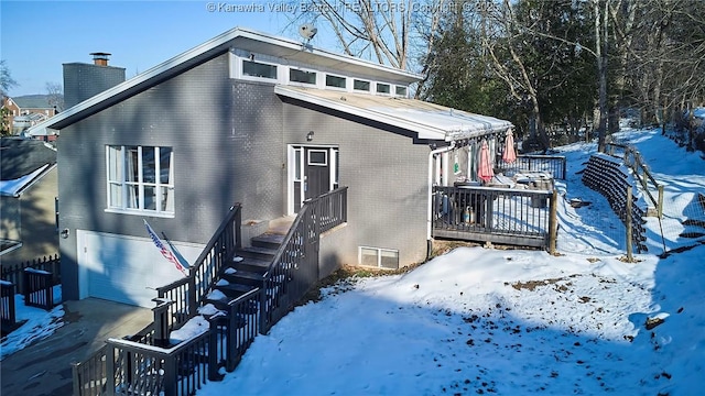 snow covered house featuring a garage and a deck