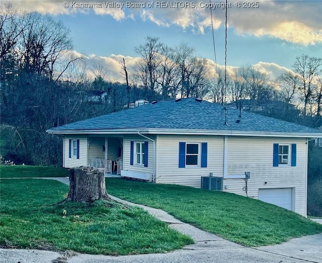 ranch-style home featuring a garage, a front lawn, central air condition unit, and covered porch