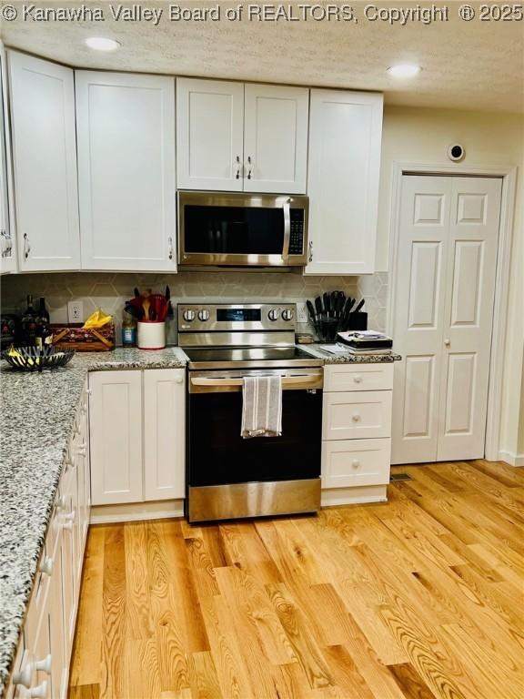 kitchen featuring decorative backsplash, white cabinets, and appliances with stainless steel finishes