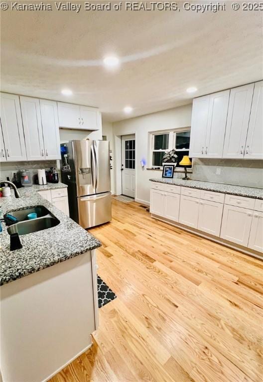 kitchen with white cabinetry, stainless steel refrigerator with ice dispenser, and sink