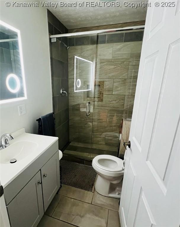 bathroom with vanity, an enclosed shower, tile patterned floors, and toilet