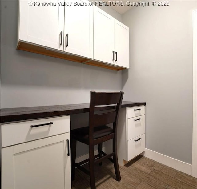 unfurnished office featuring dark hardwood / wood-style flooring and built in desk