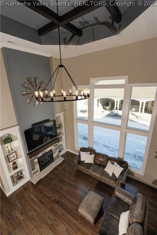 unfurnished living room with a high ceiling, a stone fireplace, a chandelier, and dark hardwood / wood-style flooring