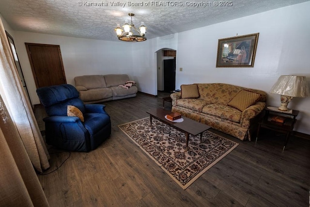 living room with dark wood-type flooring, a chandelier, and a textured ceiling