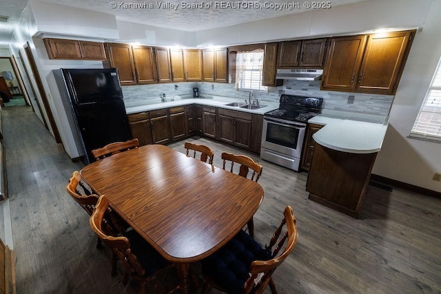 kitchen featuring a kitchen island, black refrigerator, tasteful backsplash, sink, and stainless steel electric range