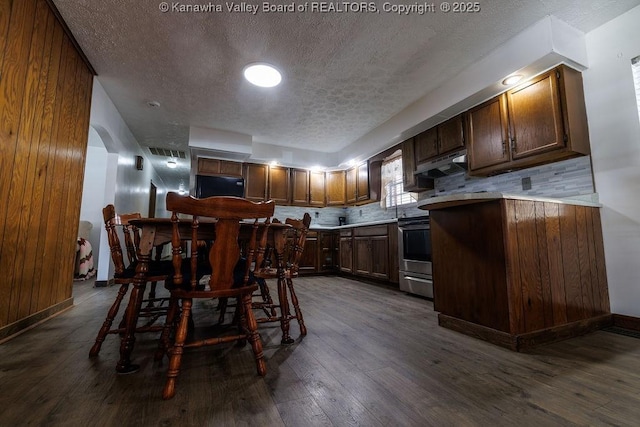 interior space with dark brown cabinetry, dark wood-type flooring, a textured ceiling, and decorative backsplash