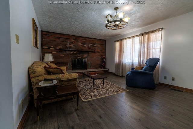 living room featuring wood-type flooring, a chandelier, a fireplace, and a textured ceiling