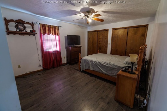 bedroom featuring dark hardwood / wood-style flooring, ceiling fan, two closets, and a textured ceiling