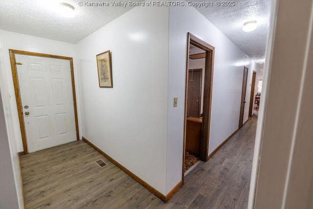 corridor with a textured ceiling and dark hardwood / wood-style flooring