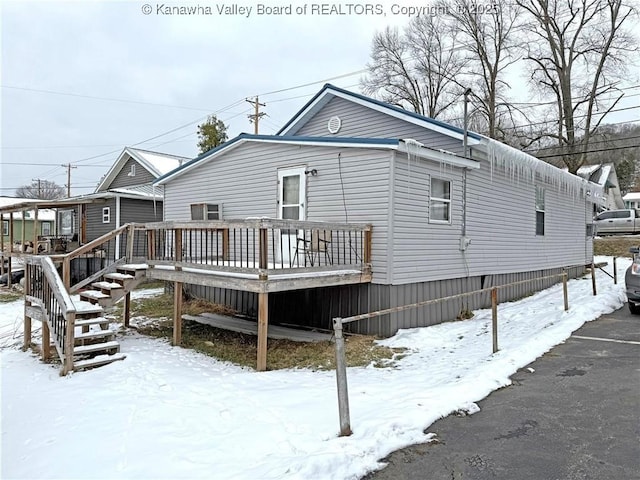 snow covered back of property with a wooden deck