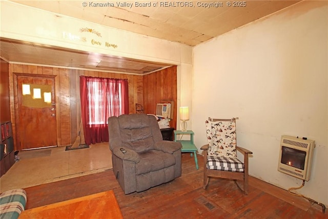 sitting room featuring heating unit, hardwood / wood-style flooring, and wood walls