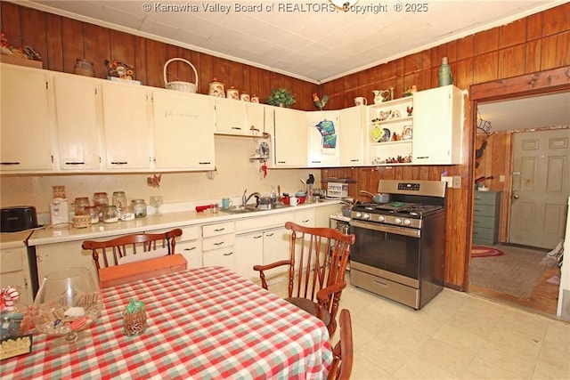 kitchen featuring white cabinetry, gas range, and wooden walls