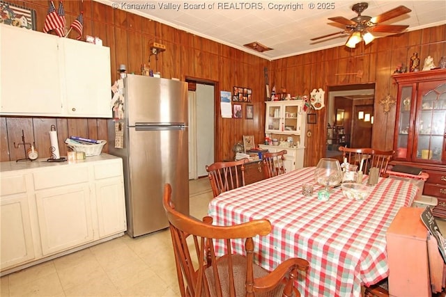 dining space featuring ornamental molding, ceiling fan, and wood walls