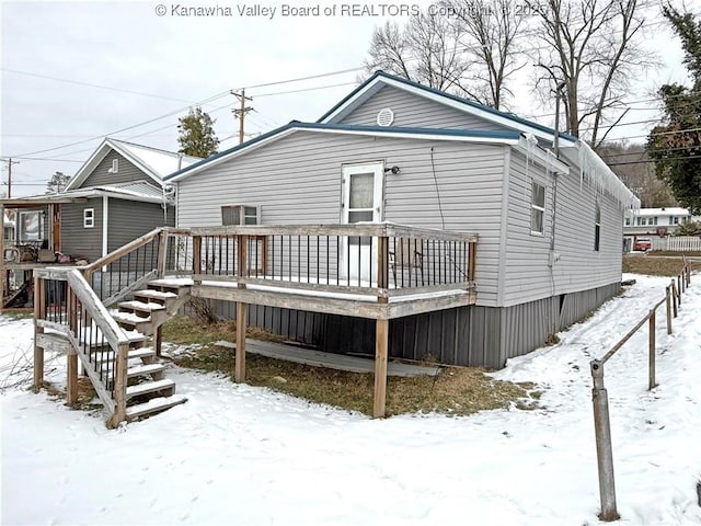 snow covered rear of property featuring a deck