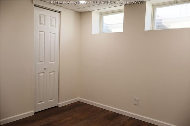 unfurnished room featuring dark hardwood / wood-style floors and a paneled ceiling